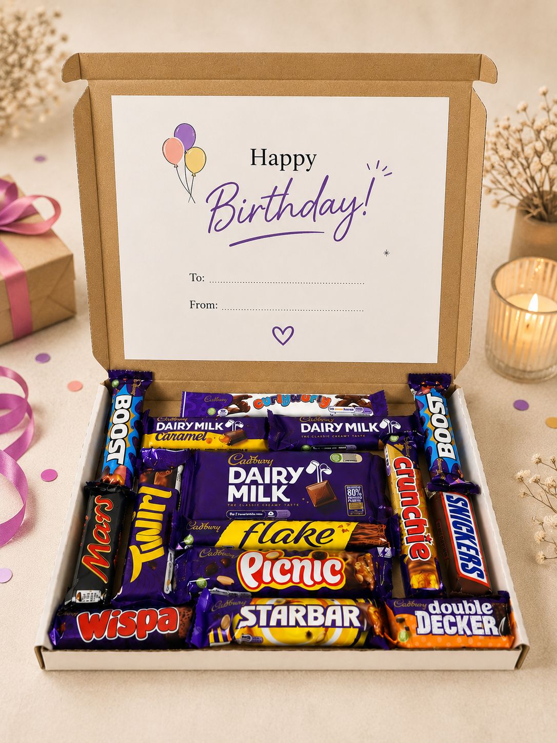A curated birthday chocolate box gift set in an open kraft cardboard box, featuring an 'Happy Birthday!' printed card inside. The box is filled with assorted popular chocolate bars including Mars, Twix, Cadbury Dairy Milk, Flakes, Snickers, Willy's, Double Decker, and Starbar.